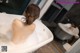 A woman sitting in a bathtub with foam on her back.