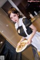 A woman holding a plate of food in a kitchen.